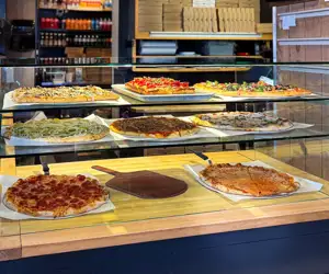 Fresh pizzas on display in the case at Joey's Pizza Pie.